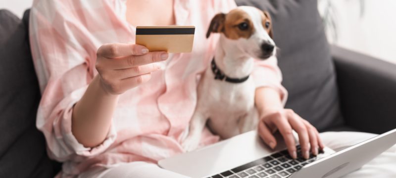 woman holding her credit card with dog on the couch